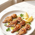 Whole octopus plated on a white dish with lemon wedges and herbs